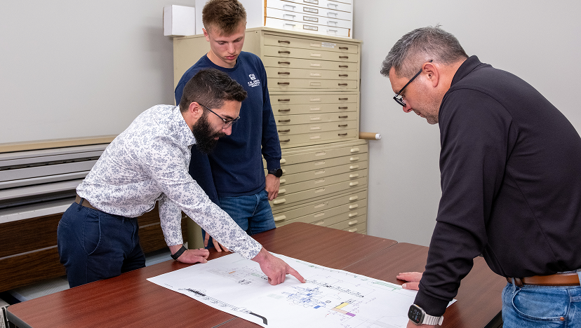 Engineers who are looking at a blueprint of F.N. Smith machinery.
